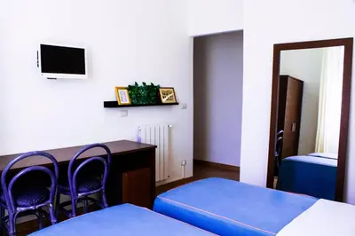 a room with two beds and a table and chairs at Hotel Anacapri in Rome
