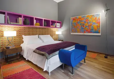 a bedroom with a large bed and a blue chair at L'obelisque maison de luxe in Rome