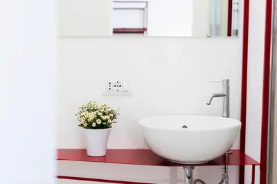 a bathroom with a white sink and a vase with flowers at Suite Cardinale in Rome