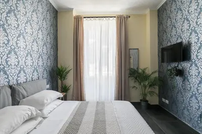 a bedroom with a bed with blue and white wallpaper at Tevere Rome Apartments in Rome