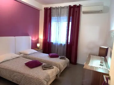a bedroom with two beds and a window with red curtains at Lungotevere Holidays in Rome