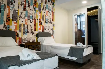 two beds in a room with a wall covered in stickers at Hostel Trastevere in Rome