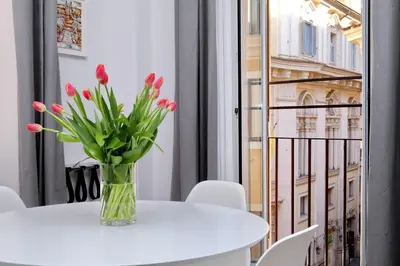 a vase of red tulips on a white table with a window at Propaganda Suites in Rome
