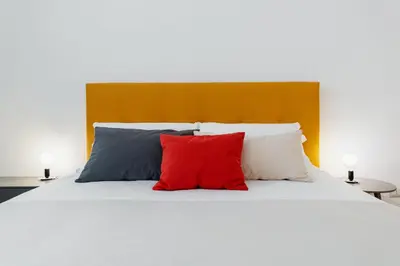 a bed with four pillows and a red pillow at Propaganda Suites in Rome