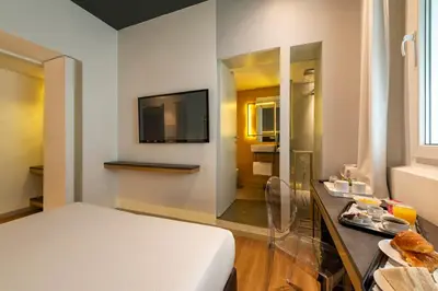 a bedroom with a bed and a tv and a bathroom at Maison Pellegrino in Rome