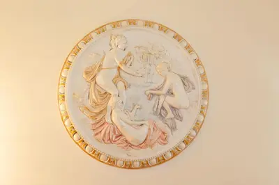 a gold and white plate with a painting of people at Hotel Suite Caesar in Rome