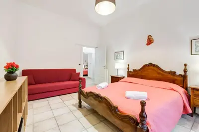 a bedroom with a bed and a red couch at Domus Ricca Termini in Rome