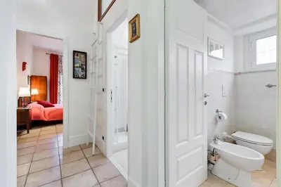 a white bathroom with a toilet and a bedroom at Domus Ricca Termini in Rome