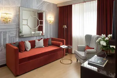 a living room with a red couch and a chair at Starhotels Michelangelo Rome in Rome