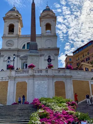 a church with a steeple and a tower with flowers at 900 Piazza del Popolo in Rome