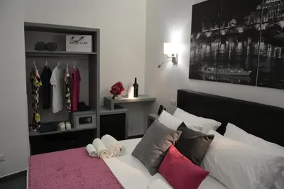 a bedroom with a bed with pillows and a shelf with clothes at Room 91-S. Peter in Rome