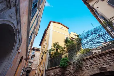 a tall yellow building with palm trees on a street at Domizio in Rome