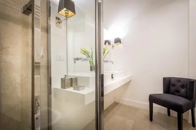 a bathroom with a shower and a chair and a sink at Old Town Apartments Rome in Rome