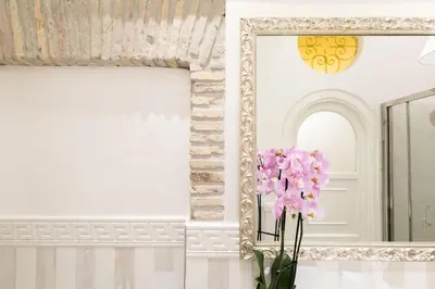 a mirror and a vase with pink flowers in a room at Sweet Life Trevi Roma in Rome
