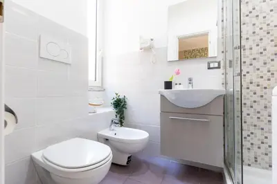 a white bathroom with a toilet and a sink at Rome as you feel - Diocleziano Apartment in Rome