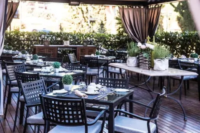 an outdoor restaurant with tables and chairs and plants at TH Roma - Carpegna Palace in Rome