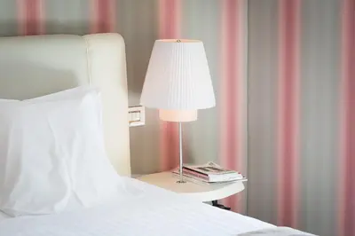 a lamp on a side table next to a bed at Grand Hotel Palace Rome in Rome
