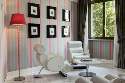 a living room with a chair and a table and a lamp at Grand Hotel Palace Rome in Rome