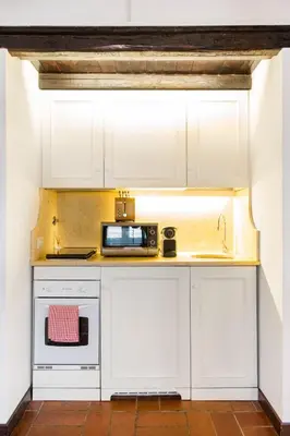 a kitchen with white cabinets and a microwave at Andreasuite Trastevere in Rome