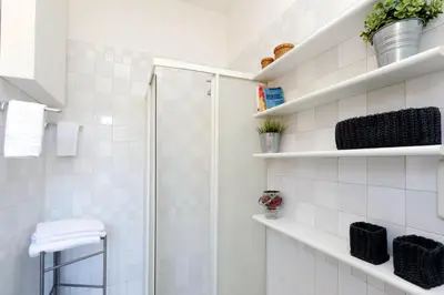 a bathroom with a shower and white tiles at Fori Imperiali Apartment in Rome