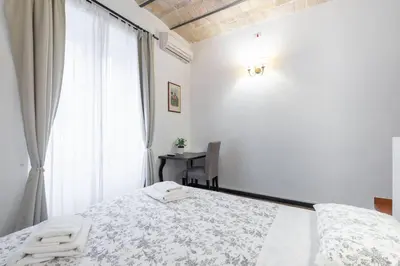 a white bedroom with a bed and a window at Steps from the Vatican Guesthouse in Rome