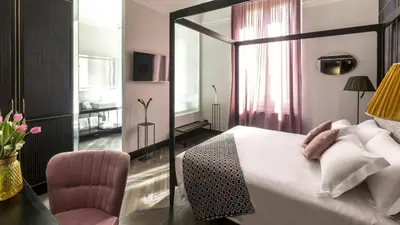 a bedroom with a bed with a mirror and a chair at Hotel The Haven Roma in Rome