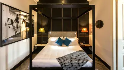 a bedroom with a black canopy bed with blue pillows at Hotel The Haven Roma in Rome
