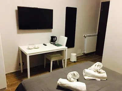 a room with a desk and a television and towels at Favola Romana - Guest House in Rome