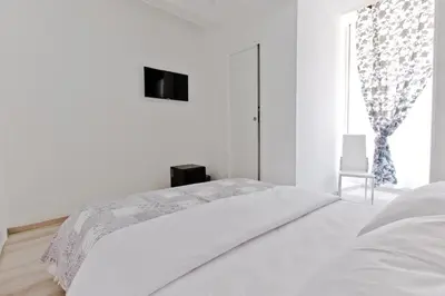 a white bedroom with a bed and a window at New Rome house 2 in Rome