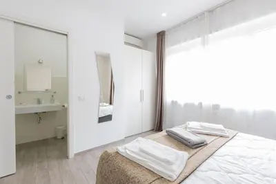 a white bedroom with a bed and a mirror at 247 Luxury Rooms Trastevere in Rome