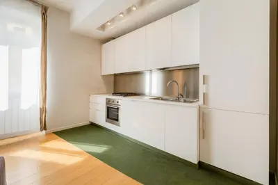 a kitchen with white cabinets and a green rug at Micol's Place, bright apt 2 rooms, 2 toilets, near metro, 80 mq in Rome