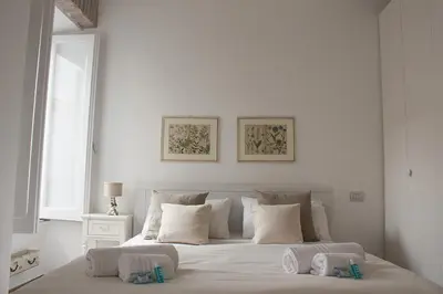 a white bedroom with a large bed with two pillows at Splendid House In Trastevere in Rome
