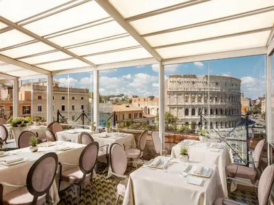 a restaurant with tables and chairs and a view of the coliseum at Hotel Palazzo Manfredi – Small Luxury Hotels of the World in Rome