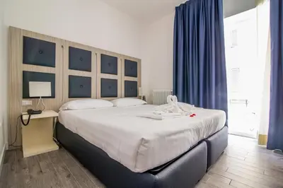 a bedroom with a large white bed with blue curtains at Vatican Relais Rome Suite in Rome