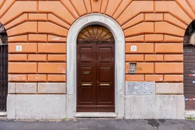 an orange brick building with a brown door at Diecipassi dal Colosseo in Rome