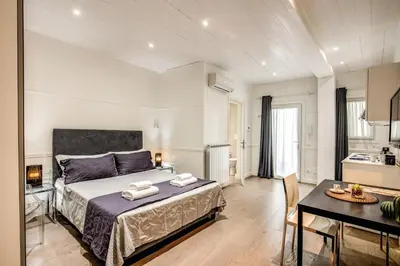 a bedroom with a bed and a table and a kitchen at Colosseo Suite Apartment in Rome