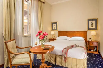 a hotel room with a bed and a table with flowers at UNA Hotels Empire Roma in Rome