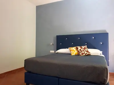 a bed with a blue headboard and pillows on it at Clodio Rooms in Rome