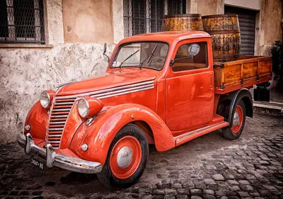 an old red truck is parked on a street at Leopardo 28 - Loft in Trastevere in Rome