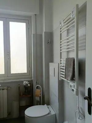 a white bathroom with a toilet and a window at Tommy Guest House Roma in Rome