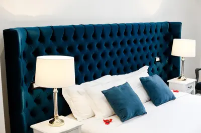 a bed with a blue headboard with pillows and lamps at Escape Luxury Suite - CA Domus Collection in Rome