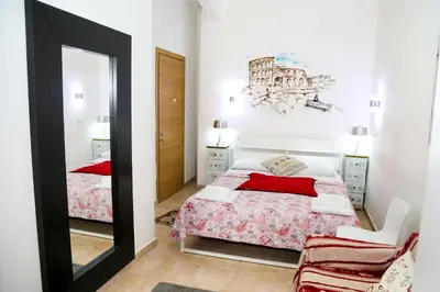 a white bedroom with a red bed and a painting on the wall at Gateway Residence in Rome