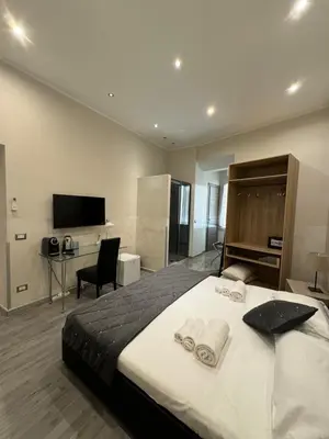 a bedroom with a bed and a desk and a television at RHS Rienzo Suites in Rome