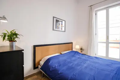 a bedroom with a blue bed and a window at Spacious Apartment with Big Terrace at Colosseum in Rome