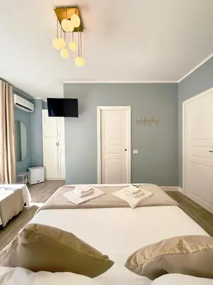 a bedroom with two beds and a tv on the wall at San Pietro Rooms 84 in Rome
