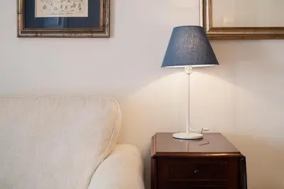 a lamp on a wooden table next to a chair at Lago Terrione Apartment - Charme Holidays in Rome