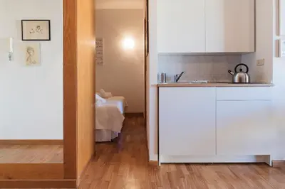a kitchen with white cabinets and a bed in a room at Lago Terrione Apartment - Charme Holidays in Rome