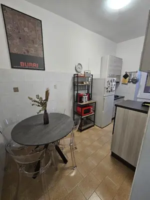 a kitchen with a table with chairs and a refrigerator at Casa Rossi Roma in Rome