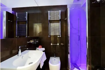 a bathroom with a sink and a shower with purple lighting at Piazza Venezia Grand Suite in Rome