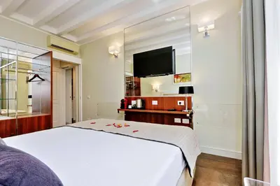 a bedroom with a white bed and a flat screen tv at Piazza Venezia Grand Suite in Rome